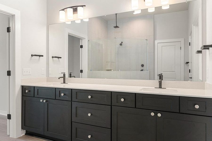 Bathroom featuring double vanity, a shower stall, and light wood-type flooring
