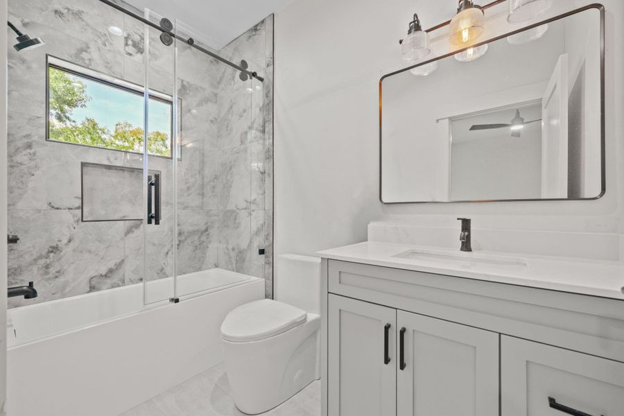 The clean, neutral palette creates a spa-like atmosphere while the well appointed layout includes a sleek vanity with ample storage, a soaking tub and premium fixtures.  Large format tiles and thoughtful lighting enhance the airy open feel. Perfect for unwinding after a long day. A must-see for buyers seeking both style and function.