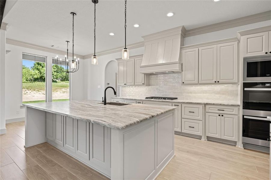 Kitchen featuring appliances with stainless steel finishes, wall chimney range hood, backsplash, an island with sink, and recessed lighting Kitchen featuring appliances with stainless steel finishes, wall chimney range hood, backsplash, an island with sink, and recessed lighting
