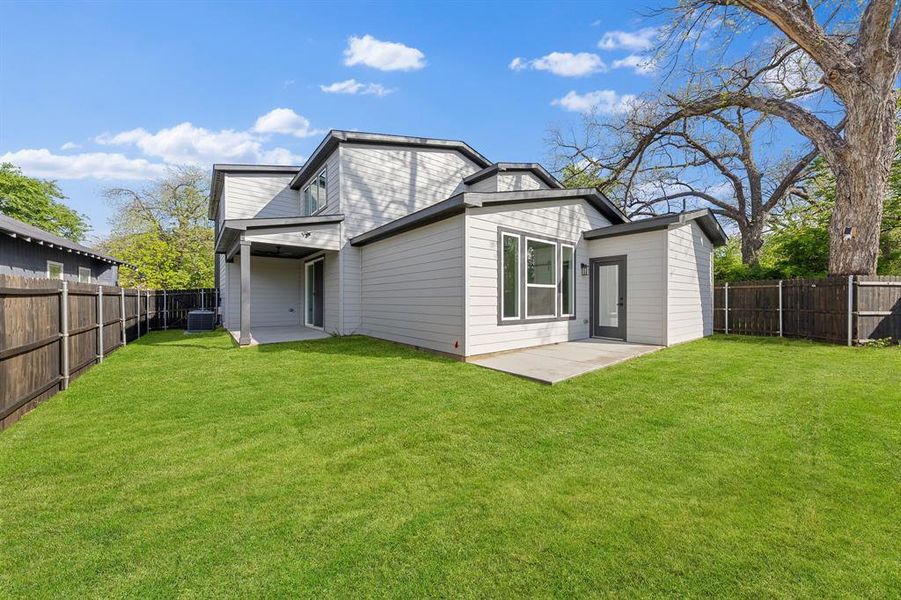 Expansive lawn area with a privacy fence, complemented by an outdoor patio and an additional covered patio space Expansive lawn area with a privacy fence, complemented by an outdoor patio and an additional covered patio space