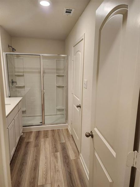 Bathroom with a stall shower, light wood-type flooring, vanity, and recessed lighting Bathroom with a stall shower, light wood-type flooring, vanity, and recessed lighting