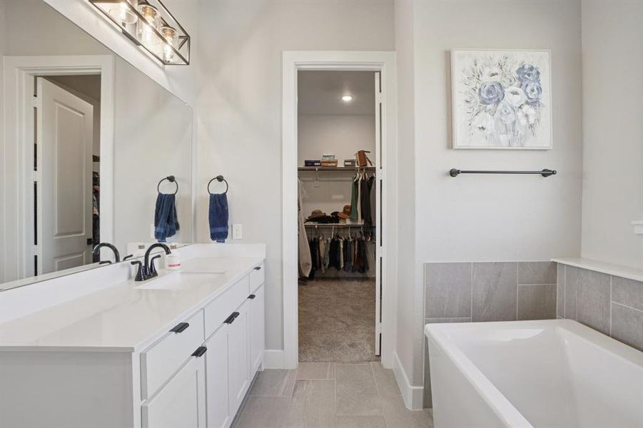 Primary bath with tiled shower, spa bath, separate vanities, and a spacious closet