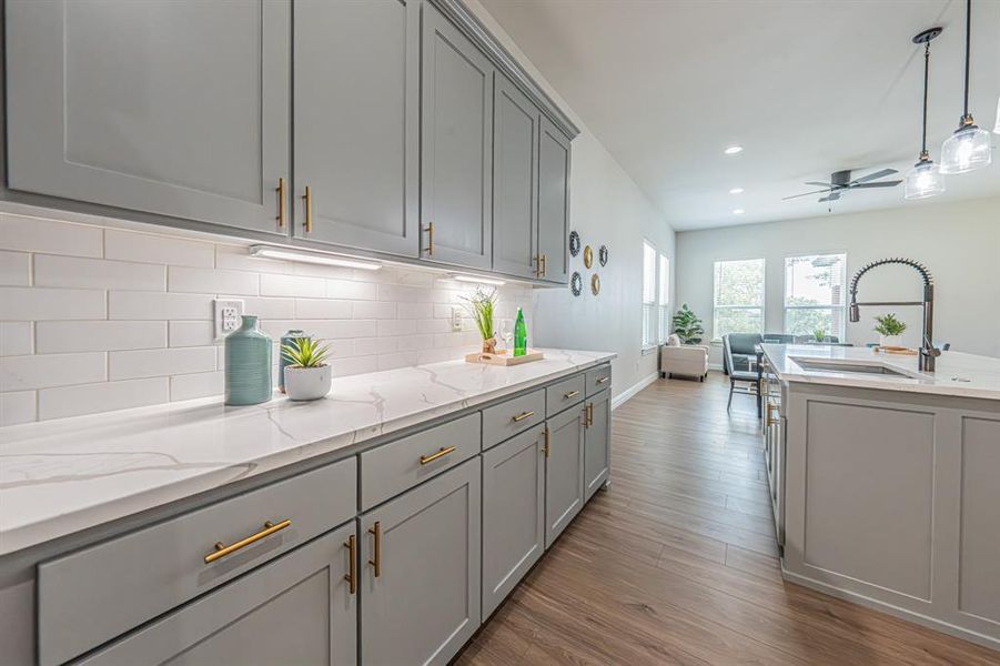 Kitchen featuring gray cabinets, decorative light fixtures, light stone counters, light wood finished floors, and recessed lighting Kitchen featuring gray cabinets, decorative light fixtures, light stone counters, light wood finished floors, and recessed lighting