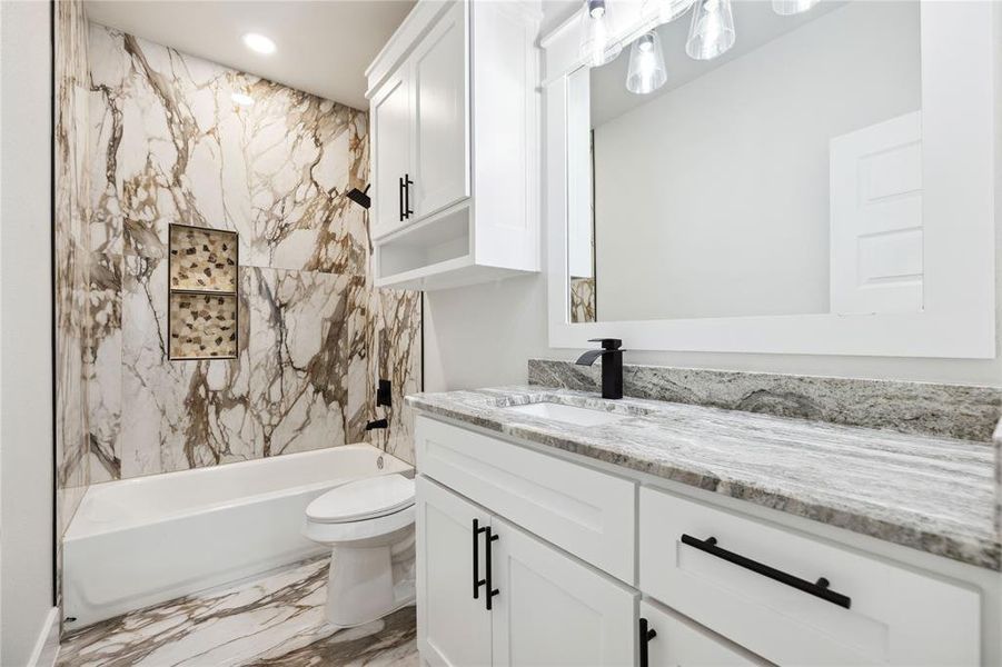 Full bathroom with vanity, tiled shower / bath combo, and toilet