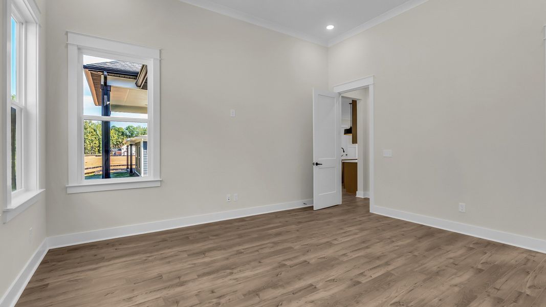 First floor bedroom with windows on multiple sides and hard surface flooring (Representative of completed home)