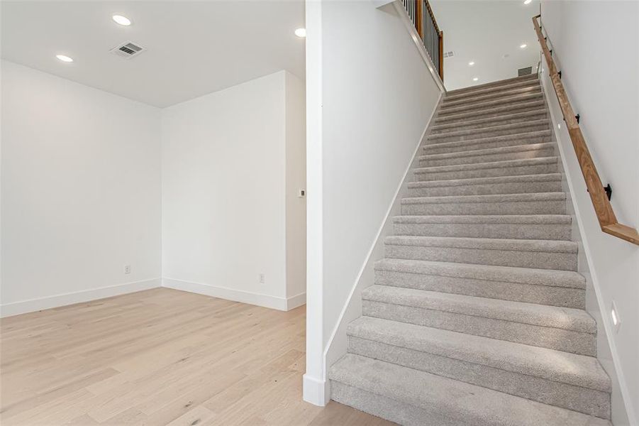 Stairs with wood finished floors, recessed lighting, and baseboards