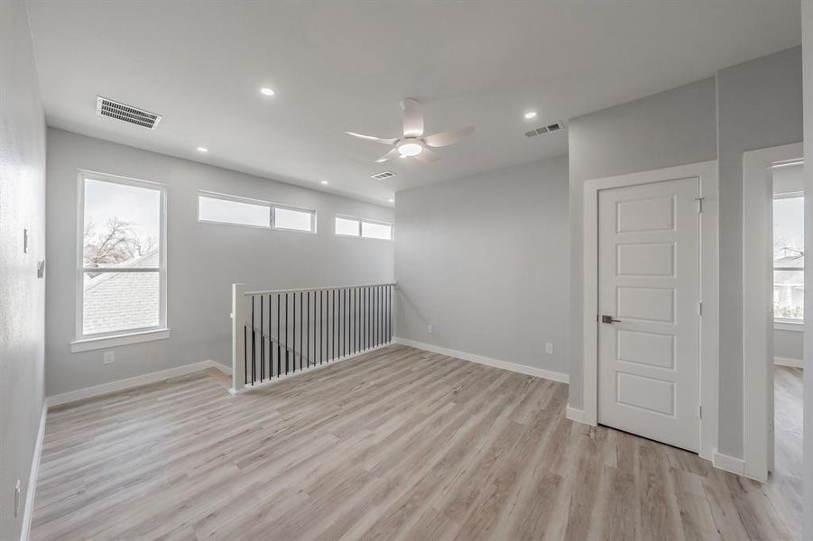 Unfurnished room featuring plenty of natural light, ceiling fan, and light wood-type flooring