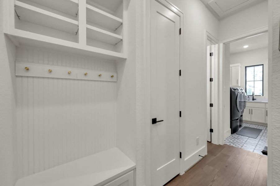 A practical drop zone just off the laundry room offers the perfect spot to hang coats, stash backpacks, and keep everyday essentials neatly organized with built-in shelving.