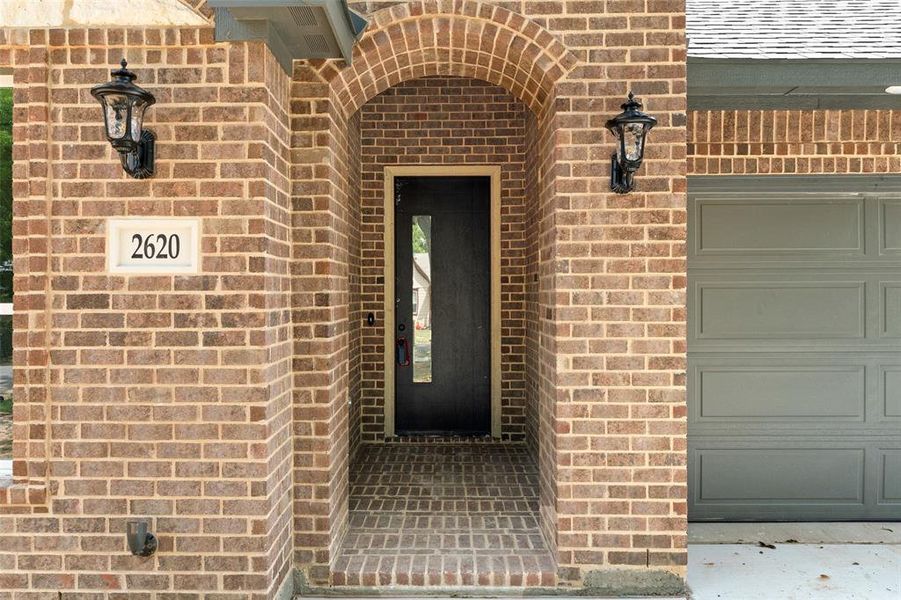 Entrance to property with brick siding and a garage