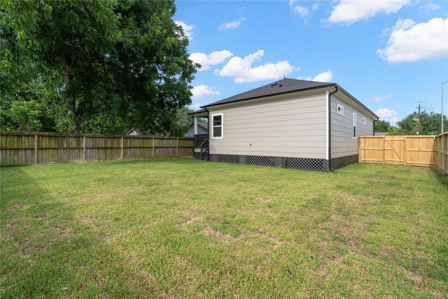 A spacious backyard with a well-maintained lawn, enclosed by a wooden fence, offering privacy and outdoor space for activities. The home's exterior features small porch area, ideal for relaxation. A spacious backyard with a well-maintained lawn, enclosed by a wooden fence, offering privacy and outdoor space for activities. The home's exterior features small porch area, ideal for relaxation.