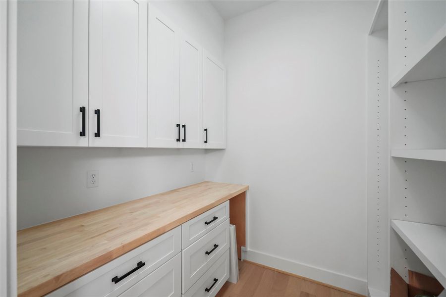 Discover a spacious pantry featuring elegant white cabinetry and a natural wood countertop. Discover a spacious pantry featuring elegant white cabinetry and a natural wood countertop.