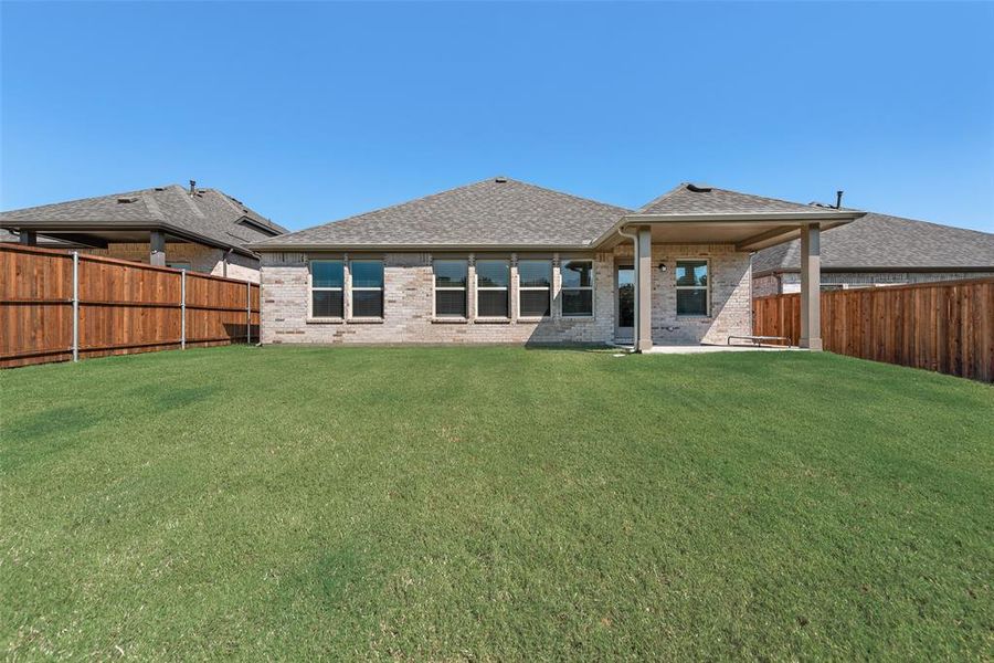 Rear view of house with brick siding, a fenced backyard, roof with shingles, and a patio area Rear view of house with brick siding, a fenced backyard, roof with shingles, and a patio area
