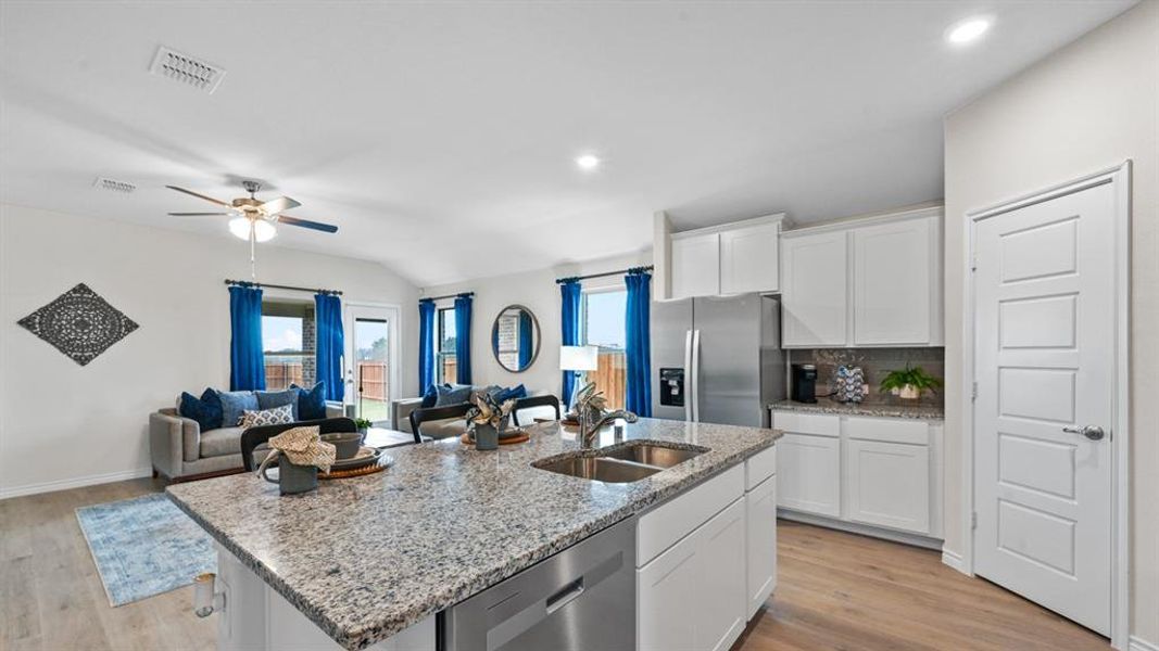Kitchen with white cabinets, light stone counters, stainless steel appliances, light wood-style floors, and open floor plan Kitchen with white cabinets, light stone counters, stainless steel appliances, light wood-style floors, and open floor plan