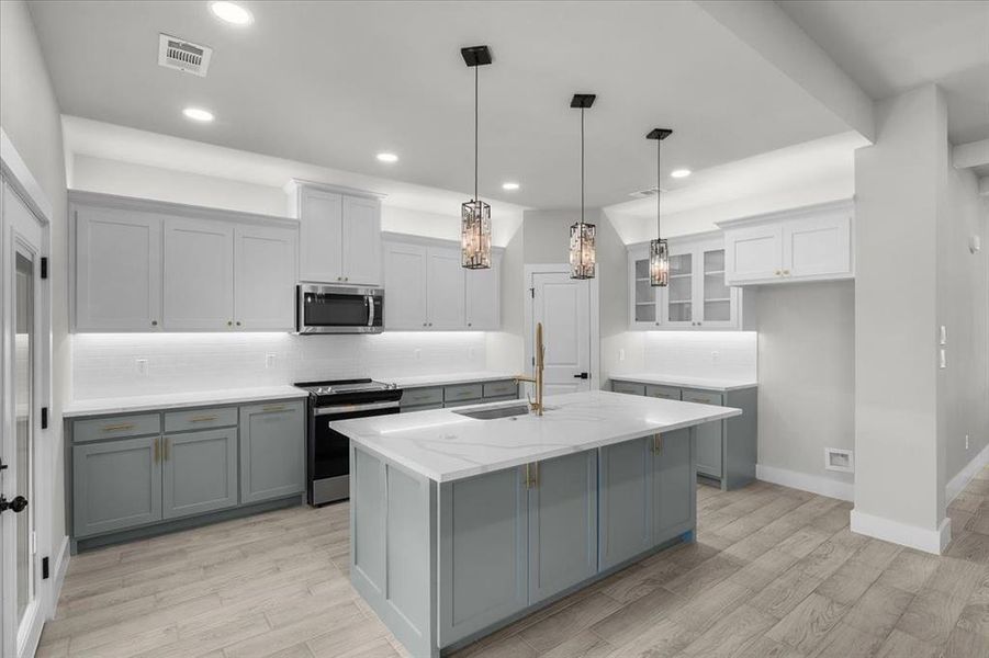 Kitchen with visible vents, light wood-style flooring, gray cabinets, stainless steel appliances, and a sink