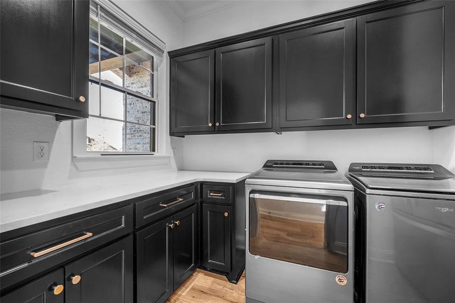 Washroom featuring washer and dryer, cabinet space, light wood-style floors, and crown molding Washroom featuring washer and dryer, cabinet space, light wood-style floors, and crown molding