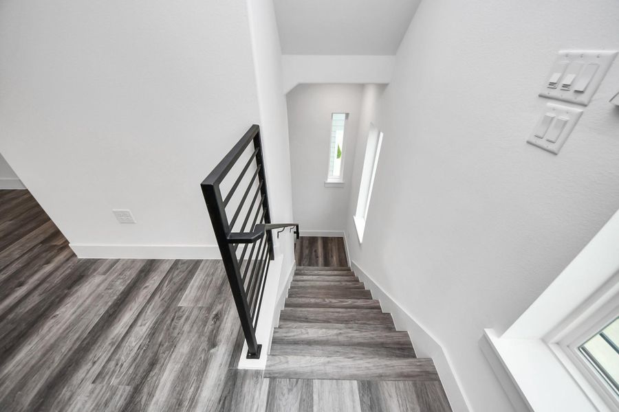 This modern staircase features sleek, dark wooden steps and a black metal railing, complemented by natural light from a vertical window, creating a bright and contemporary feel. This modern staircase features sleek, dark wooden steps and a black metal railing, complemented by natural light from a vertical window, creating a bright and contemporary feel.