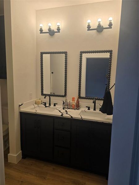 Bathroom featuring double vanity and dark wood-style flooring