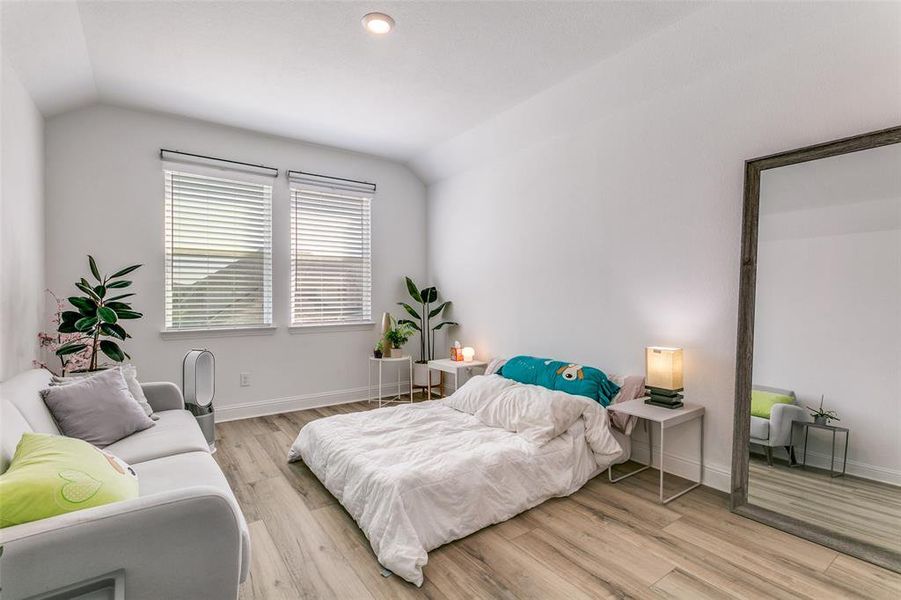 Bedroom featuring vaulted ceiling, light wood finished floors, and recessed lighting