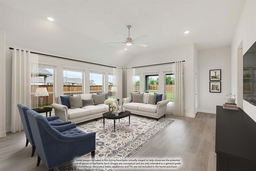 Bright living room with vaulted ceiling, ceiling fan, hardwood floors, and large windows overlooking backyard Bright living room with vaulted ceiling, ceiling fan, hardwood floors, and large windows overlooking backyard