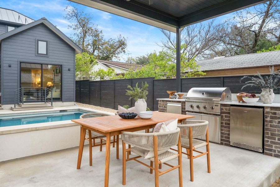 Fenced backyard with a patio, outdoor dining area, and exterior kitchen
