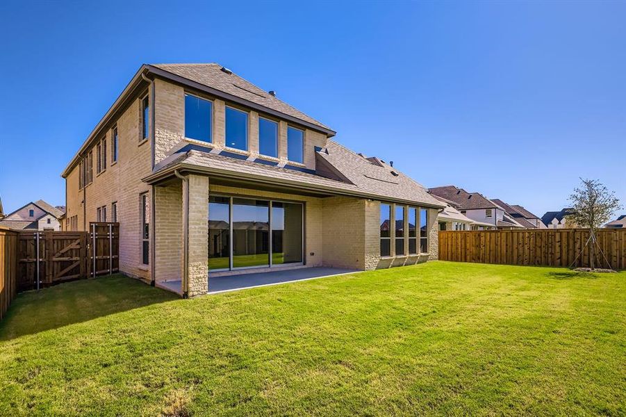 Back of house featuring a shingled roof, a patio area, a gate, and brick siding