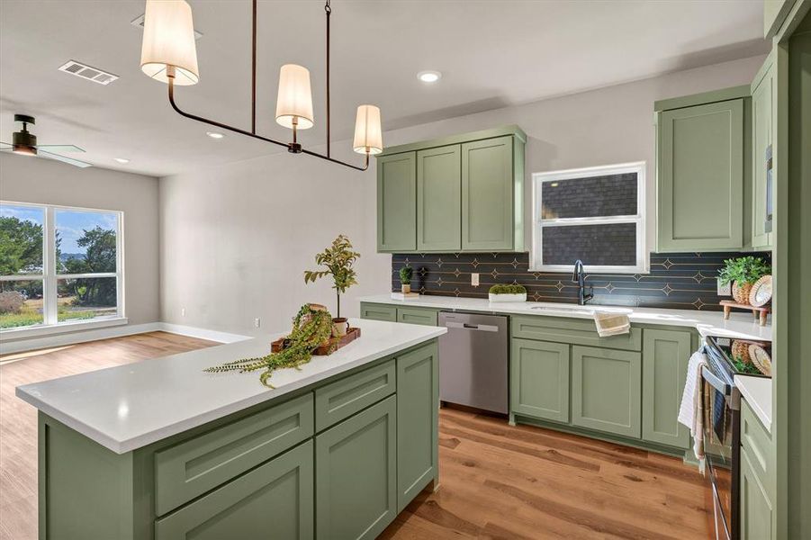 Kitchen featuring green cabinets, light wood-style flooring, decorative light fixtures, stainless steel appliances, and recessed lighting Kitchen featuring green cabinets, light wood-style flooring, decorative light fixtures, stainless steel appliances, and recessed lighting