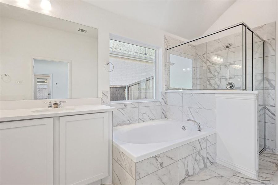 Bathroom with vanity, shower with separate bathtub, and lofted ceiling