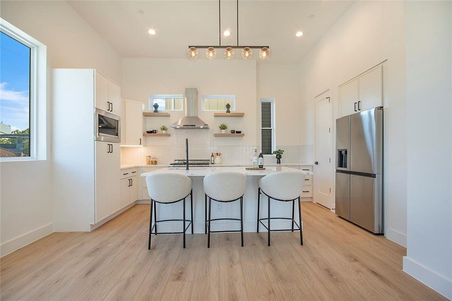 Kitchen with decorative light fixtures, a center island with sink, white cabinets, tasteful backsplash, and recessed lighting Kitchen with decorative light fixtures, a center island with sink, white cabinets, tasteful backsplash, and recessed lighting