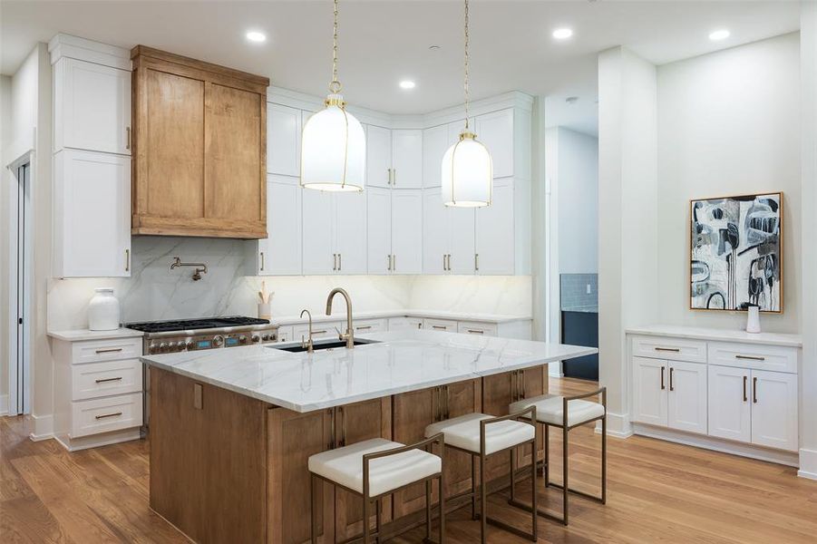 Kitchen with sink, white cabinetry, an island with sink, and light wood-type flooring