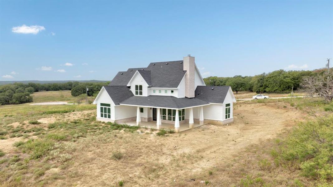 Back of property with a patio area, roof with shingles, driveway, and a chimney Back of property with a patio area, roof with shingles, driveway, and a chimney