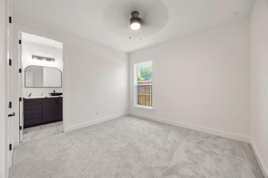 Carpeted room with a single window, white walls, and a ceiling fan Carpeted room with a single window, white walls, and a ceiling fan