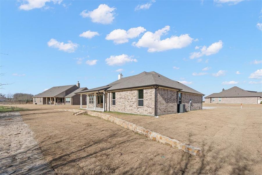 Rear view of property featuring brick siding and a patio area