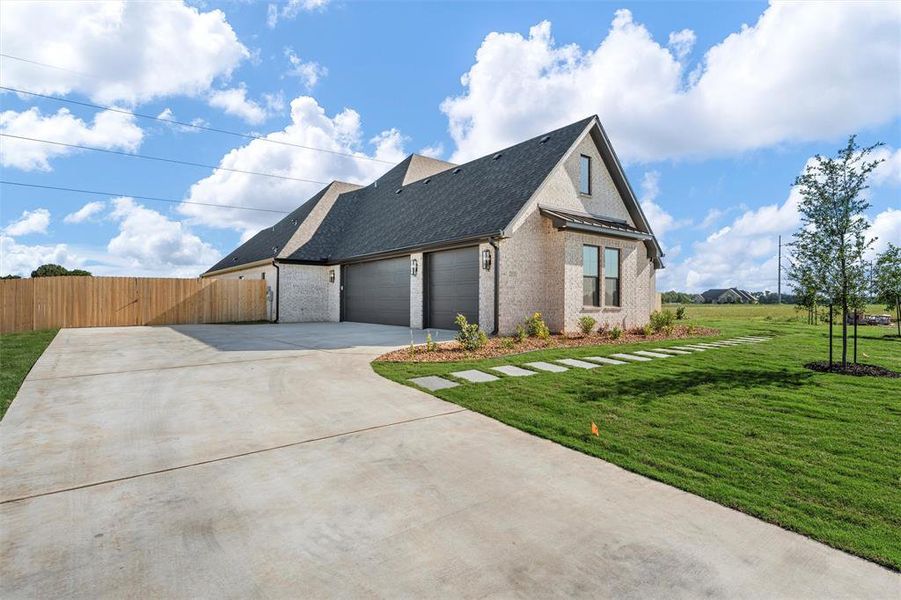View of property exterior with brick siding, driveway, roof with shingles, and an attached garage
