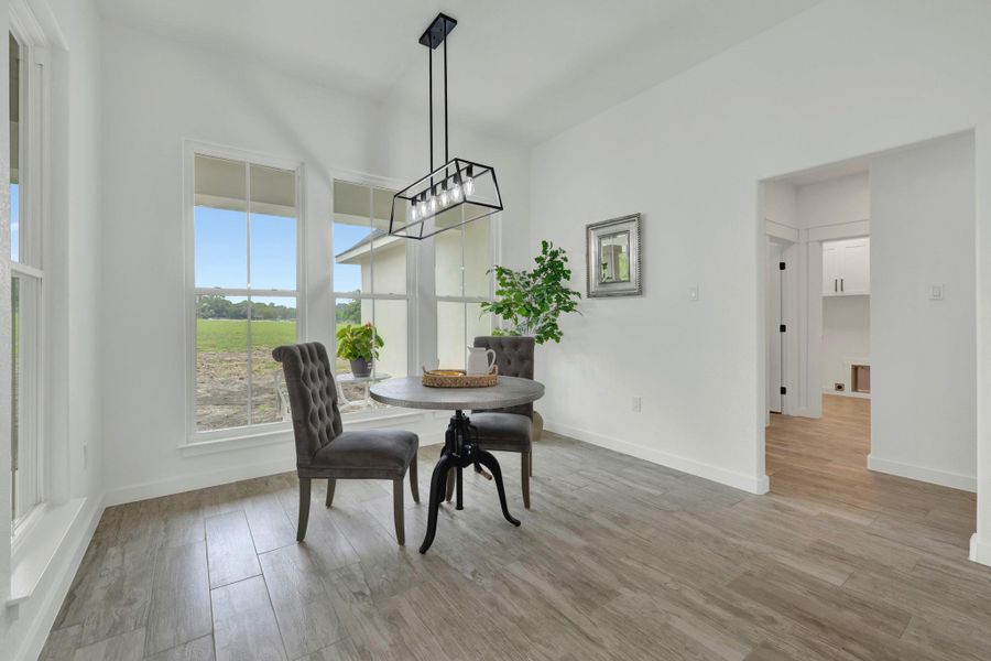 Dining area featuring wood-finish flooring, multiple large windows, and a modern linear chandelier