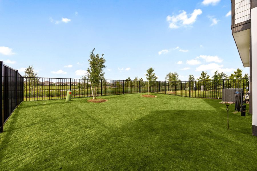 Lush yard with two trees overlooking the greenspace behind