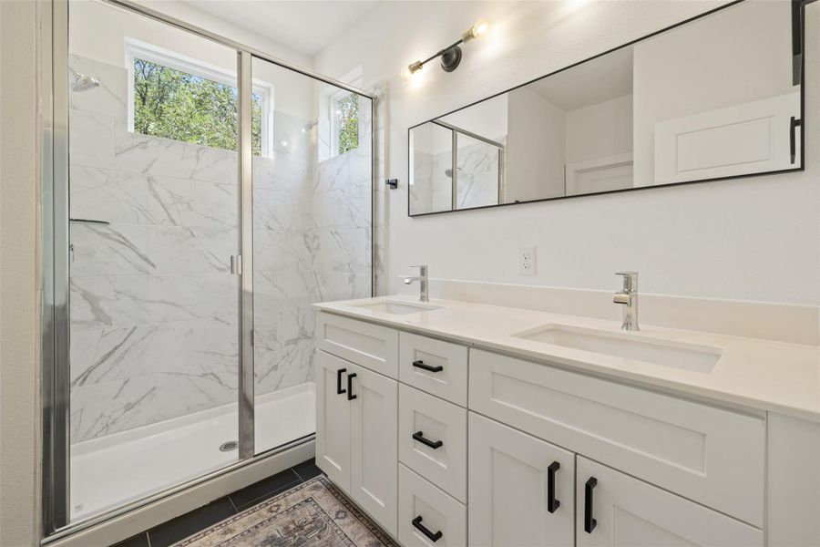 Bathroom with a marble finish shower, double vanity, and tile patterned flooring Bathroom with a marble finish shower, double vanity, and tile patterned flooring