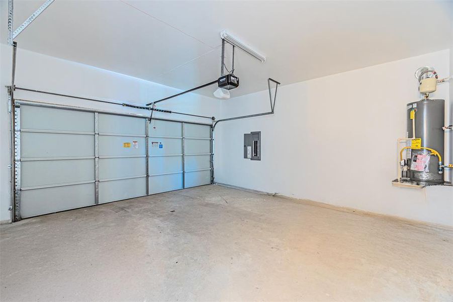 Garage featuring electric panel, water heater, and a garage door opener Garage featuring electric panel, water heater, and a garage door opener