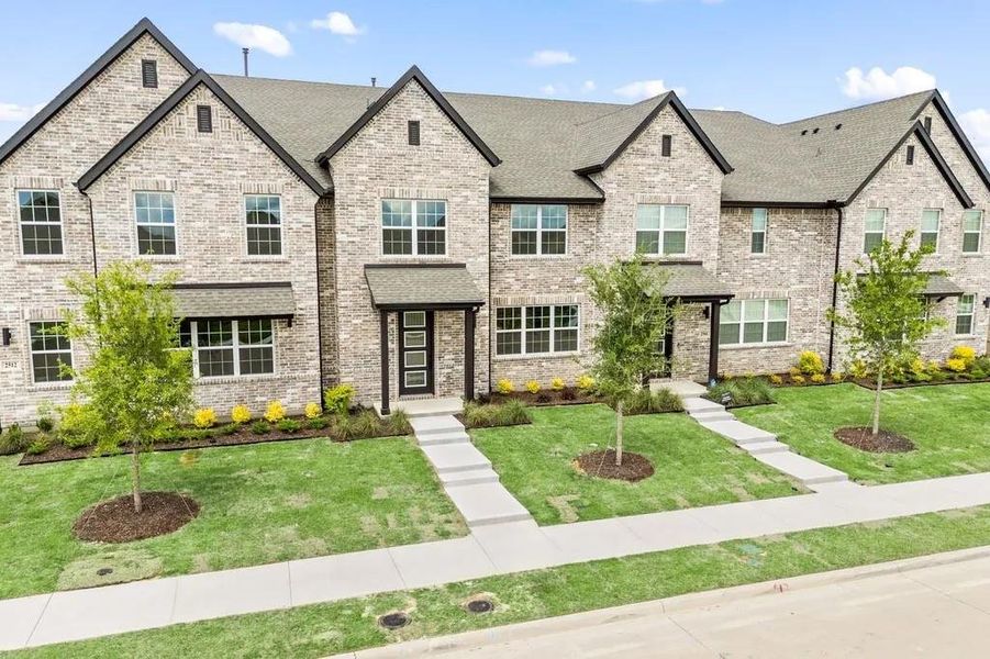 French country style house featuring brick siding, roof with shingles, and a front lawn