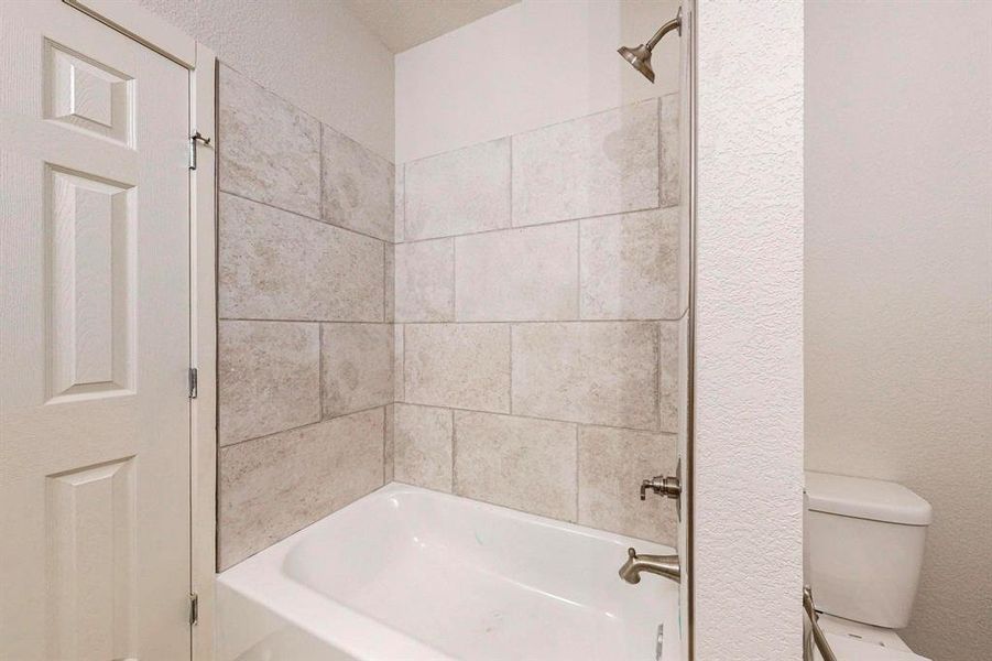 Bathroom featuring toilet and tiled shower / bath