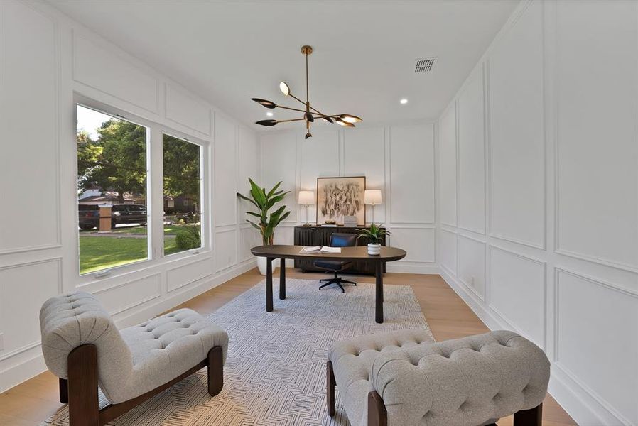 Bright interior space featuring extensive wall paneling, light wood-finish flooring, and a modern ceiling fixture
