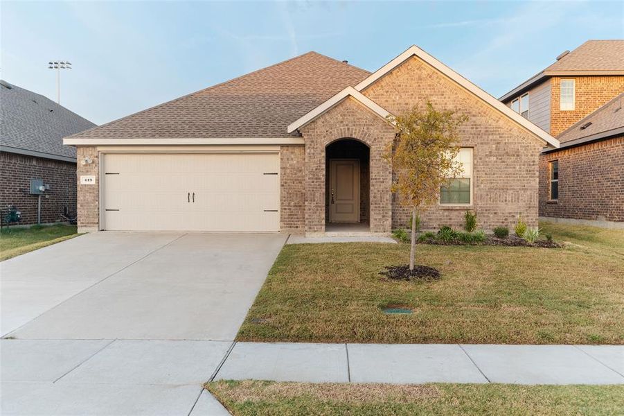 View of front of home with a front yard, roof with shingles, brick siding, and concrete driveway View of front of home with a front yard, roof with shingles, brick siding, and concrete driveway
