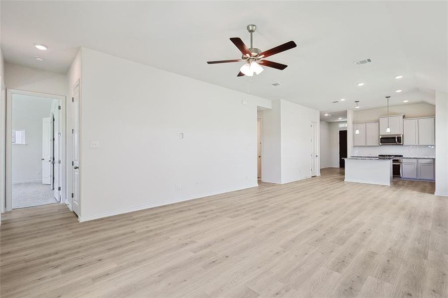 Unfurnished living room with lofted ceiling, ceiling fan, and light hardwood / wood-style flooring