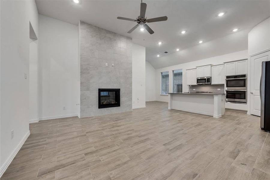 Unfurnished living room with ceiling fan, tile walls, and a tile fireplace