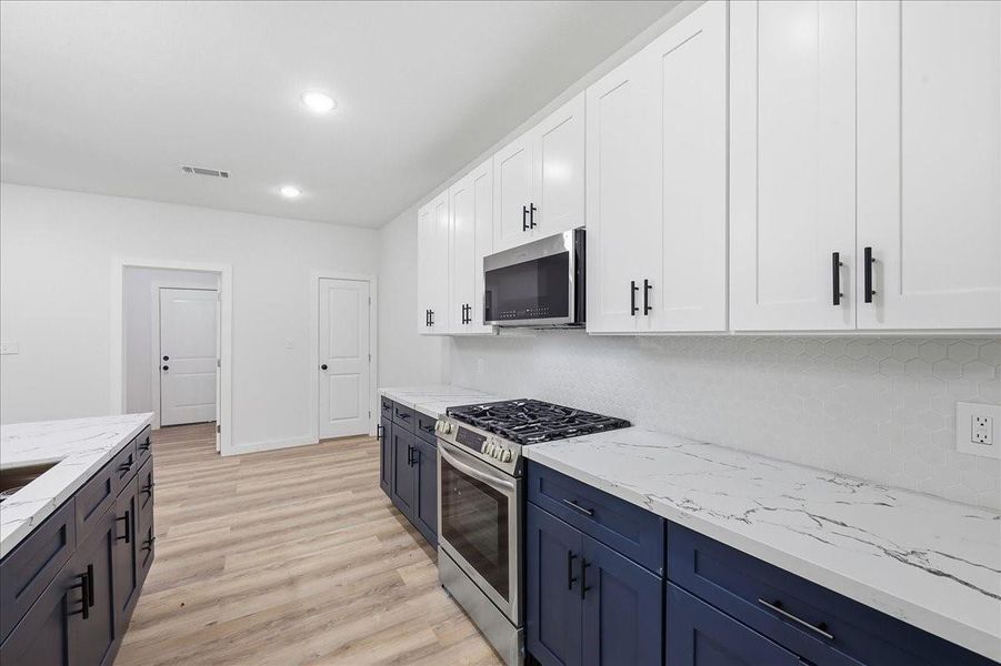 Closer view of the kitchen workspaces highlighting modern tile backsplashes and contemporary hardware. Closer view of the kitchen workspaces highlighting modern tile backsplashes and contemporary hardware.