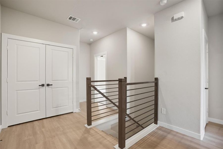 Hallway featuring an upstairs landing, light wood-type flooring, and recessed lighting Hallway featuring an upstairs landing, light wood-type flooring, and recessed lighting