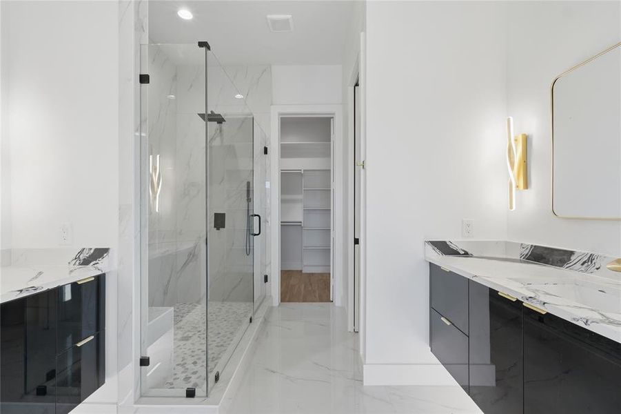 Full bathroom with double vanity, a walk in closet, a marble finish shower, light marble finish flooring, and recessed lighting Full bathroom with double vanity, a walk in closet, a marble finish shower, light marble finish flooring, and recessed lighting
