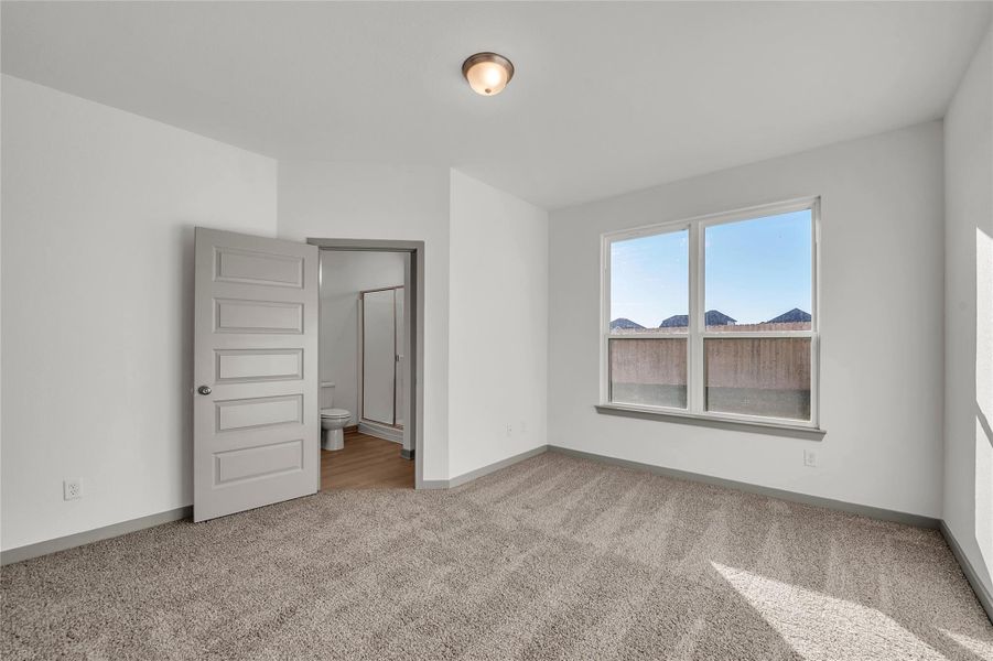 Unfurnished bedroom featuring ensuite bathroom and light colored carpet