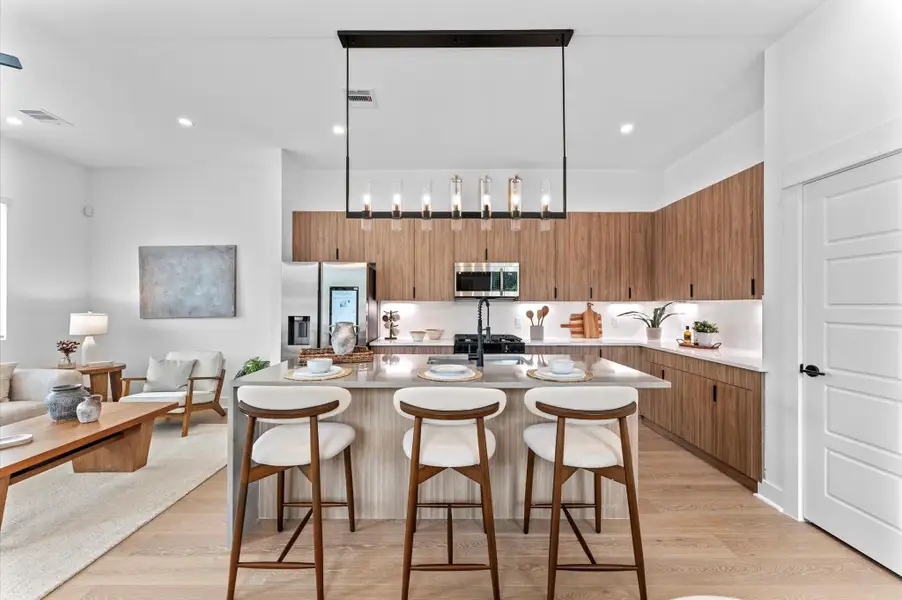 Striking and modern kitchen island serves as the centerpiece of this open-concept culinary space, featuring a waterfall quartz countertop that flows seamlessly down one side for a sculptural, high-end look. The island is framed by minimalist cabinetry in matte finishes, paired with bold pendant lighting that adds a touch of sophistication. Integrated bar seating invites casual dining and conversation, while the clean lines and neutral palette enhance the island’s sleek aesthetic. Striking and modern kitchen island serves as the centerpiece of this open-concept culinary space, featuring a waterfall quartz countertop that flows seamlessly down one side for a sculptural, high-end look. The island is framed by minimalist cabinetry in matte finishes, paired with bold pendant lighting that adds a touch of sophistication. Integrated bar seating invites casual dining and conversation, while the clean lines and neutral palette enhance the island’s sleek aesthetic.