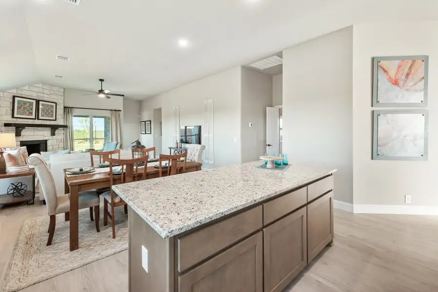 Kitchen island with granite countertop open to dining area and living room with stone fireplace Kitchen island with granite countertop open to dining area and living room with stone fireplace