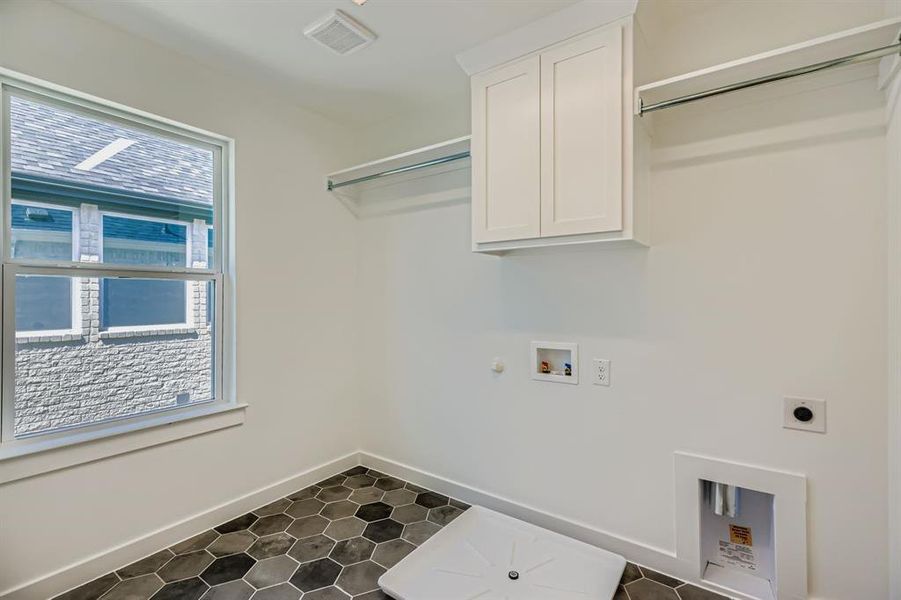 Laundry area with electric dryer hookup, hookup for a gas dryer, washer hookup, cabinet space, and dark tile patterned flooring
